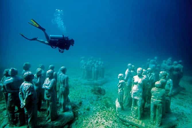 Scuba diver exploring underwater statues at the MUSA museum in Cancun's clear waters